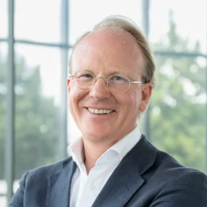 Porträt von CEO Nikolaus Külps mit Brille und Sakko vor großen Fenstern.
