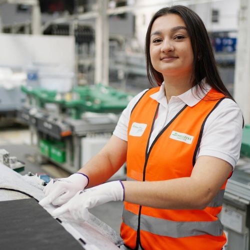 Start 1 Junge Frau in Sicherheitsweste bei Schnellecke arbeitet im Lager an einem Teil.